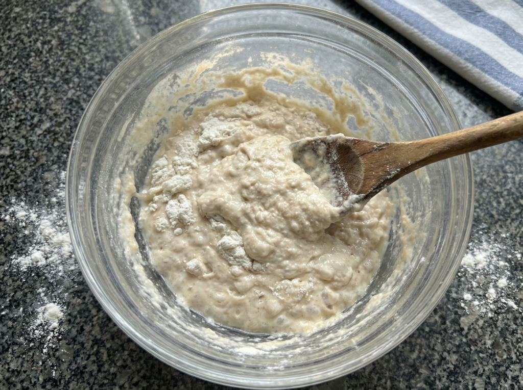 Mixing wet and sticky high hydration ciabatta dough in a bowl, looking like a shaggy mess.