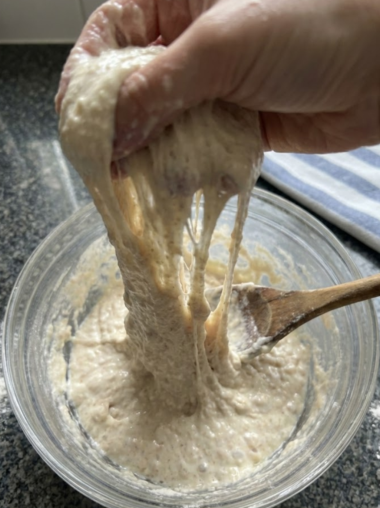 Demonstrating the stretch and fold technique on wet ciabatta dough to build gluten strength without kneading.